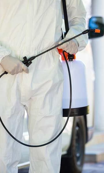 photo of a person in coveralls holding a spray wand